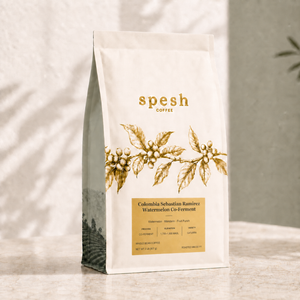 A bag of Spesh Coffee, Colombia Sebastian Ramírez Watermelon Co-Ferment, standing on a light marble surface against a textured wall with soft shadow patterns.