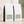 Two white bulk 5 lb coffee bags with black side panels and pale green labels, arranged on a beige surface against a textured wall with soft shadow overlays. The front bags show the text 