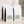 Four bulk white 5 lb coffee bags with black side panels and pale green labels, arranged on a beige surface against a textured wall with soft shadow overlays. The front bags show the text 