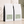 Two bulk 5 lb white coffee bags with black side panels and pale green labels, arranged on a beige surface against a textured wall with soft shadow overlays. The front bags show the text 