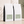 Two white bulk 5 lb coffee bags with black side panels and pale sage green labels, arranged on a light beige surface against a softly textured beige wall with leaf shadows. Kenya Kiamugumo