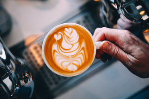 Hand holding a latte with latte art